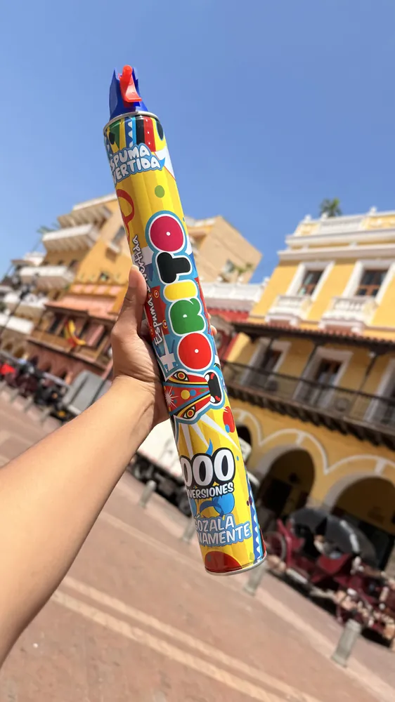 Mano sosteniendo una lata de Espuma Torito entre balcones coloniales